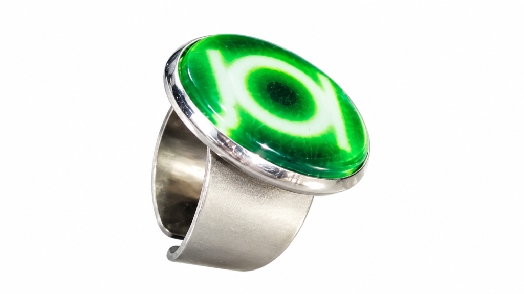 Silver ring featuring a large green glass cabochon stone with a white symbol against a white background.
