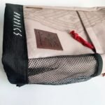 Tan beige backpack with black mesh side pocket and Nordics branding patch.